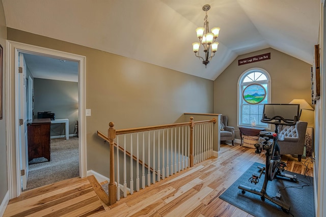 workout room featuring an inviting chandelier, baseboards, lofted ceiling, and wood finished floors
