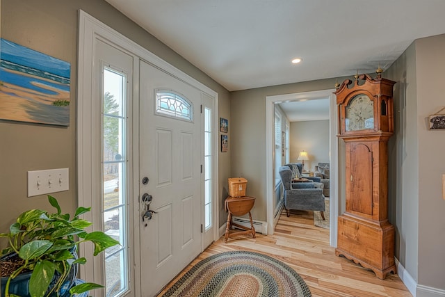 foyer entrance featuring a baseboard radiator, recessed lighting, light wood-style floors, and baseboards