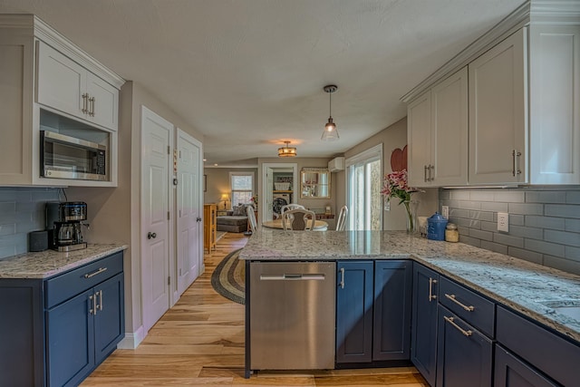 kitchen featuring light wood finished floors, a peninsula, blue cabinets, and stainless steel appliances