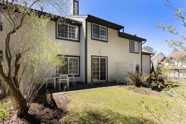 rear view of property with a patio, a yard, and a chimney