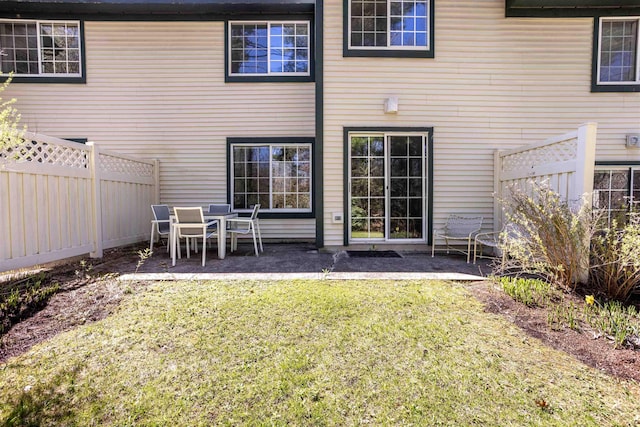 rear view of property featuring a yard, a patio, and a fenced backyard