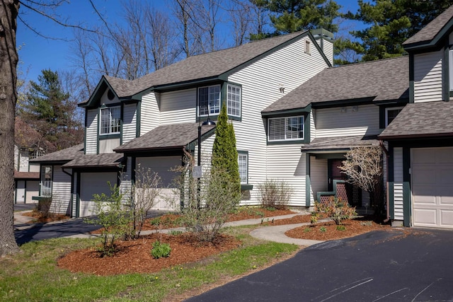 view of front of home featuring an attached garage, driveway, and a shingled roof
