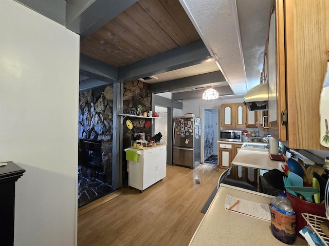 kitchen with range hood, light wood-style flooring, light countertops, appliances with stainless steel finishes, and beam ceiling
