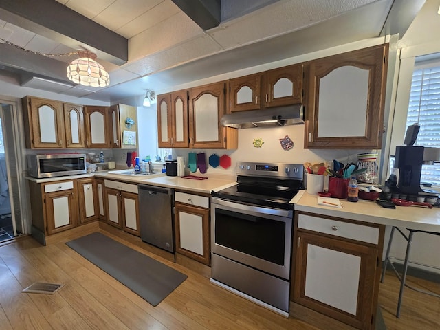 kitchen featuring light countertops, under cabinet range hood, a sink, and appliances with stainless steel finishes