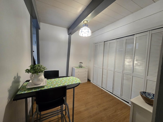 dining space featuring wood finished floors and beam ceiling
