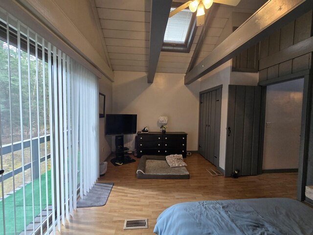 bedroom with wood finished floors, visible vents, beamed ceiling, a skylight, and high vaulted ceiling