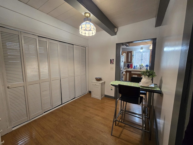 interior space featuring baseboards, wood finished floors, and beam ceiling