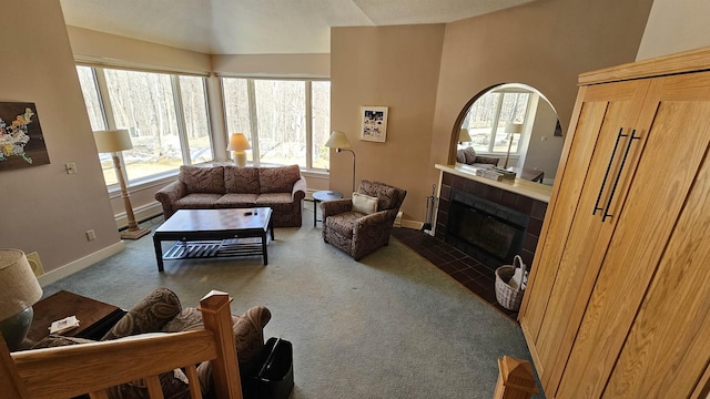 carpeted living room featuring baseboards and a fireplace