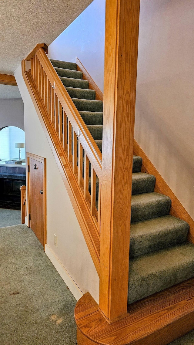 stairs featuring baseboards, carpet flooring, and a textured ceiling