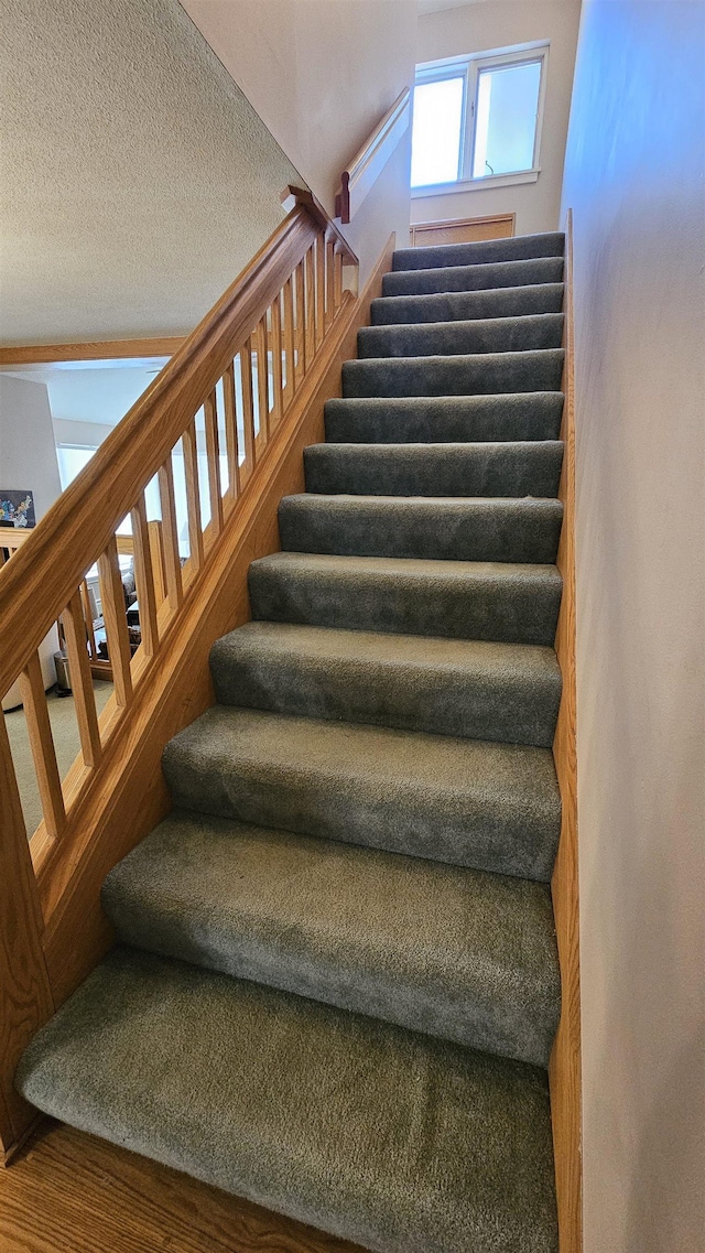stairway featuring a textured ceiling and wood finished floors