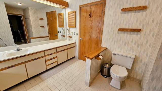 bathroom featuring toilet, vanity, tile patterned flooring, and wallpapered walls
