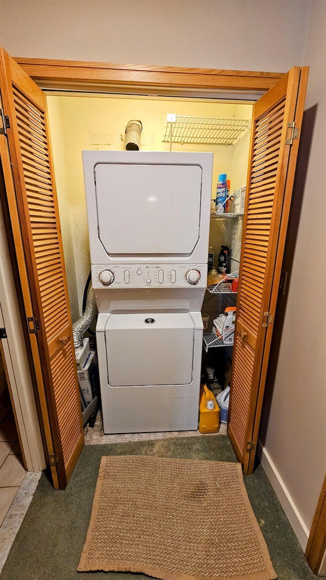 laundry area with baseboards, stacked washer / dryer, and laundry area