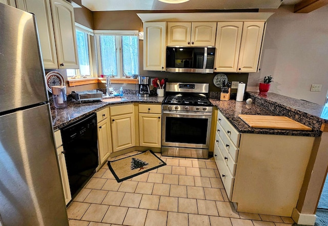 kitchen featuring light tile patterned floors, a sink, appliances with stainless steel finishes, and a peninsula