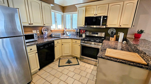 kitchen with light tile patterned flooring, dark stone counters, and appliances with stainless steel finishes