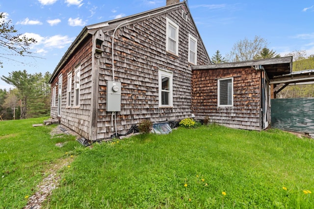 back of house featuring a chimney and a lawn
