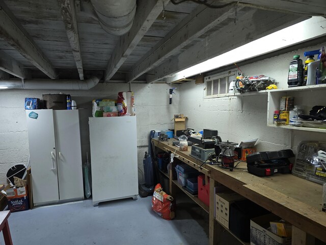 unfinished basement with a workshop area and white fridge