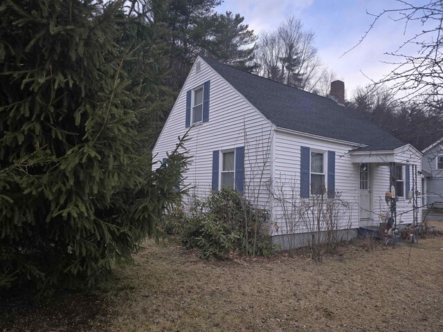 view of side of property with a chimney and roof with shingles