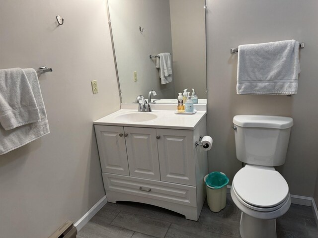 half bath with toilet, vanity, and baseboards