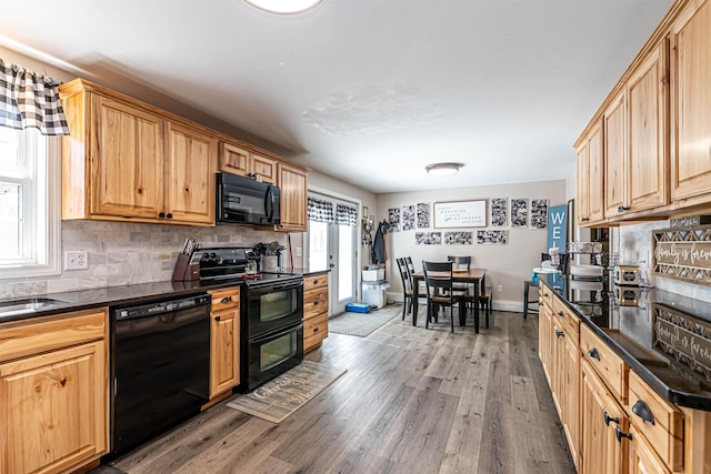 kitchen with wood finished floors, dark countertops, backsplash, and black appliances