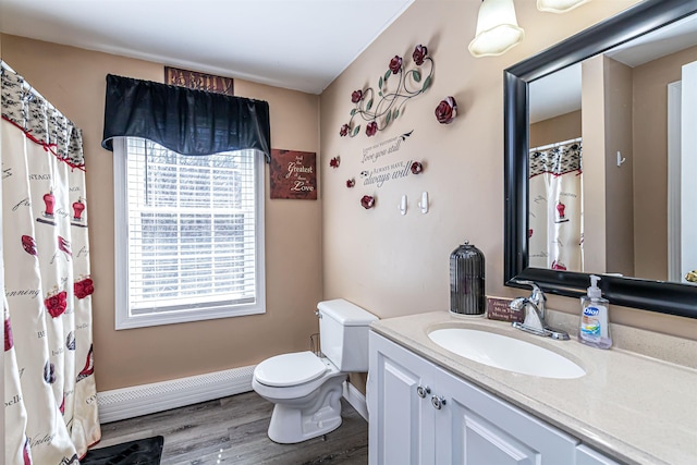 bathroom featuring vanity, baseboard heating, toilet, wood finished floors, and baseboards