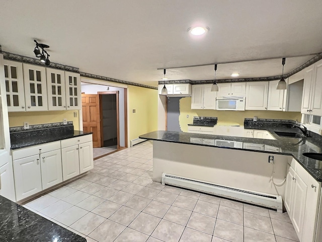 kitchen with light tile patterned floors, a sink, white microwave, glass insert cabinets, and baseboard heating