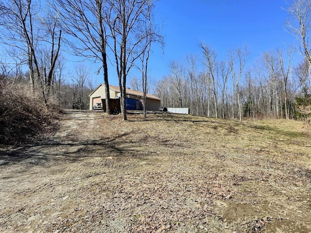 view of yard featuring an outbuilding, dirt driveway, and a garage