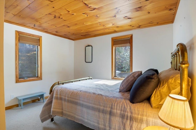 carpeted bedroom with baseboards, wood ceiling, and ornamental molding