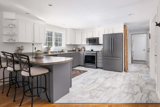 72 Natures Way, Wells, ME 04090 - kitchen with stainless steel appliances, a peninsula, white cabinets, dark countertops, and a breakfast bar