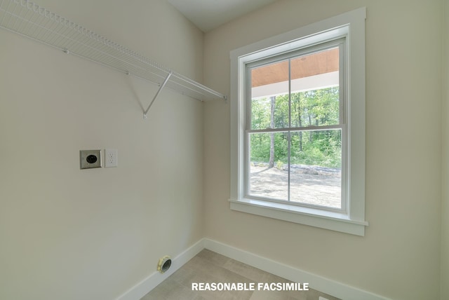 washroom with hookup for an electric dryer, baseboards, and laundry area
