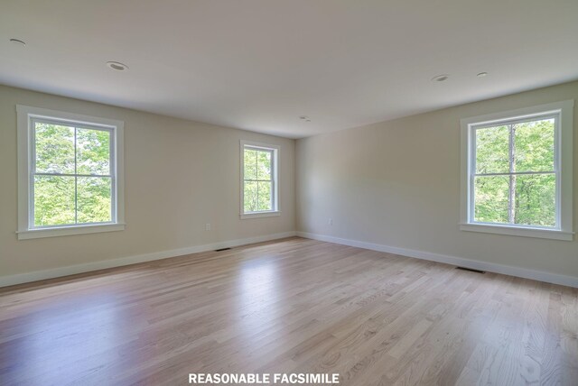spare room featuring light wood-style flooring, baseboards, and visible vents