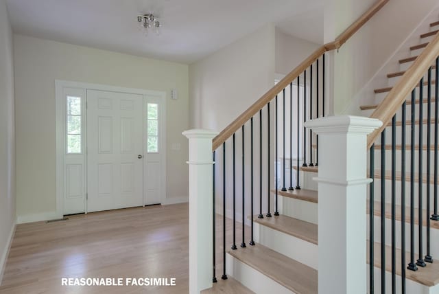 foyer featuring baseboards, stairs, and wood finished floors