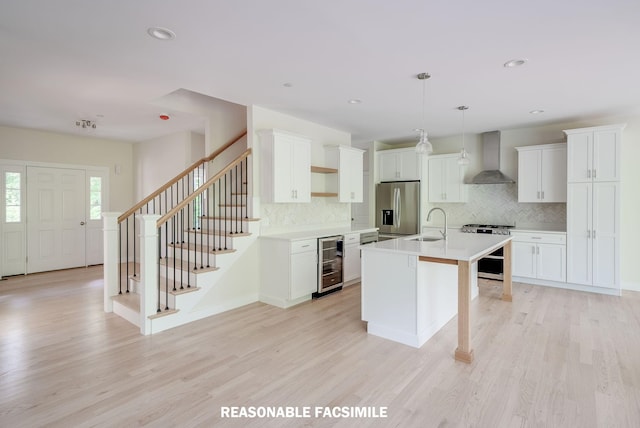 kitchen featuring wine cooler, a sink, stainless steel fridge with ice dispenser, wall chimney exhaust hood, and gas range