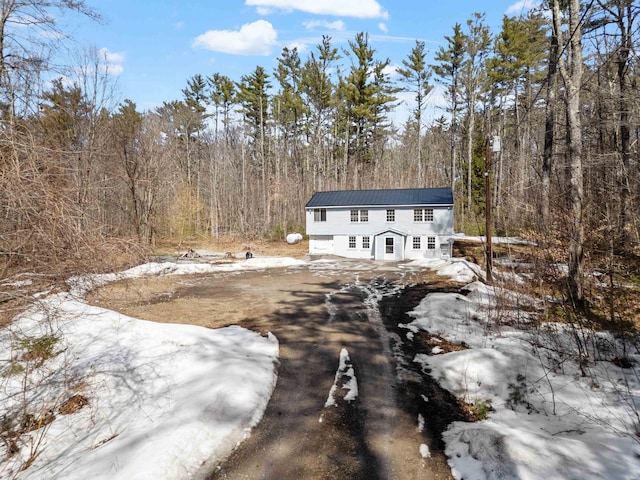 view of front of house featuring metal roof and a forest view