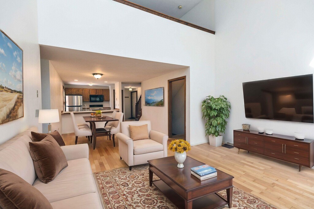 living room with a towering ceiling, baseboards, and light wood-style floors
