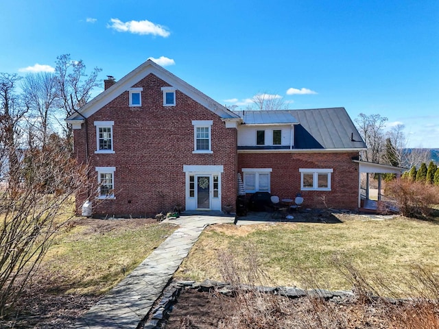 14 Adams Landing Rd, Grand Isle, VT 05458 - rear view of property featuring a standing seam roof, a chimney, brick siding, metal roof, and a lawn