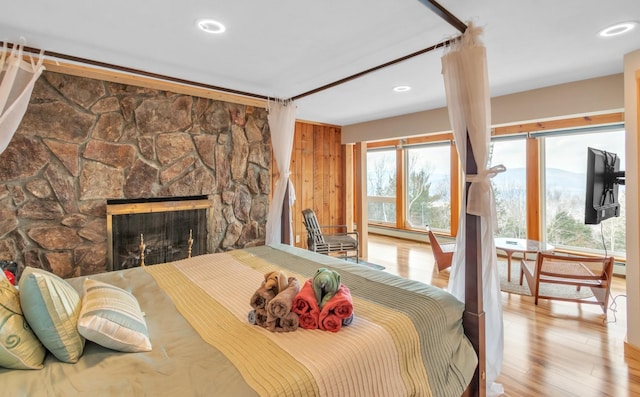 bedroom with baseboard heating, a fireplace, wood finished floors, and recessed lighting