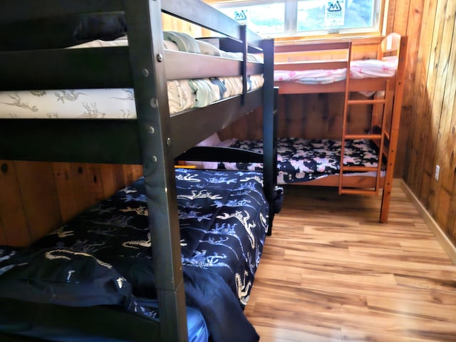 bedroom with wood walls and wood finished floors