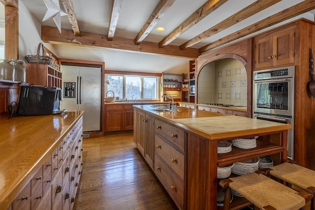 kitchen featuring wood counters, beamed ceiling, dark wood finished floors, stainless steel appliances, and a sink