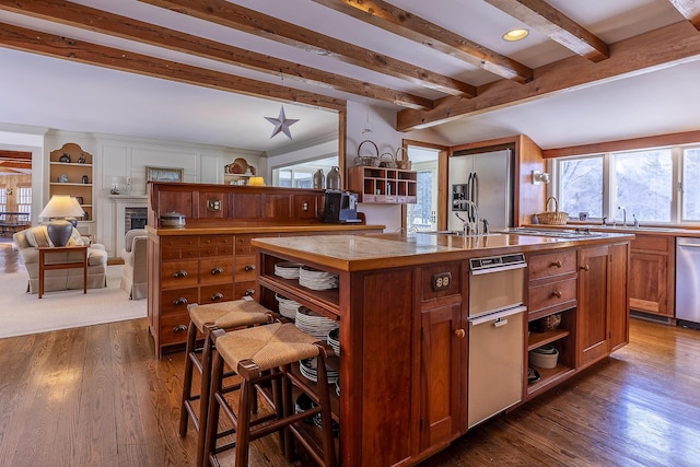 kitchen featuring dark wood-style floors, appliances with stainless steel finishes, a kitchen island with sink, and open shelves