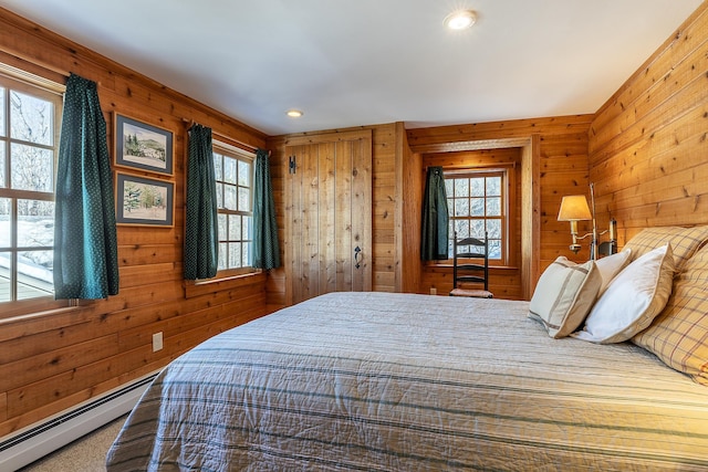 bedroom with wood walls, a baseboard heating unit, and recessed lighting