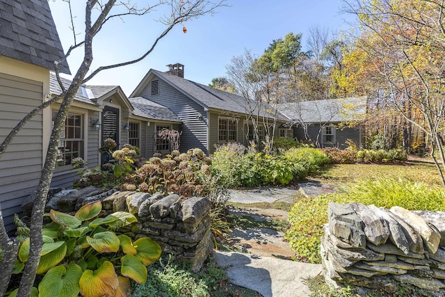 back of house with a shingled roof and a chimney