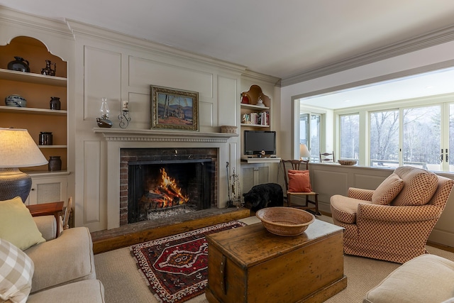 living room featuring built in shelves, a brick fireplace, and crown molding