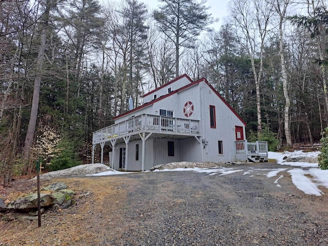 view of front facade featuring a wooden deck and gravel driveway