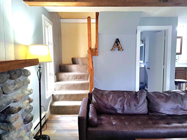 living room featuring a baseboard radiator, wood finished floors, and stairs
