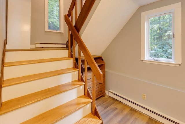 stairs featuring a baseboard radiator, wood finished floors, and lofted ceiling