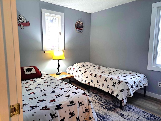 bedroom with baseboards, a textured ceiling, and wood finished floors