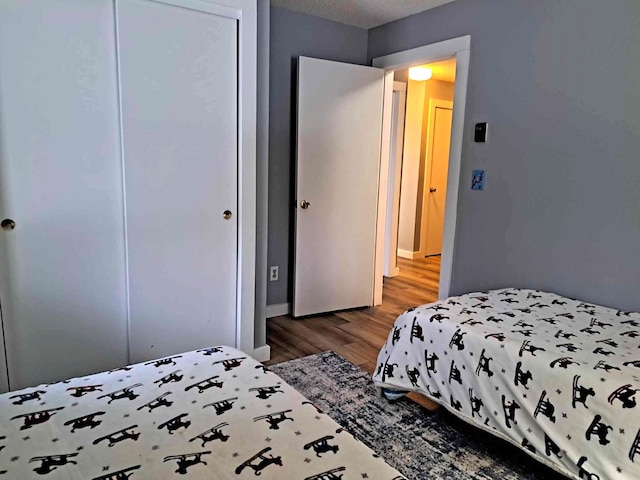 bedroom with wood finished floors, a closet, and baseboards