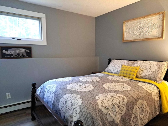 bedroom featuring wood finished floors and a baseboard heating unit