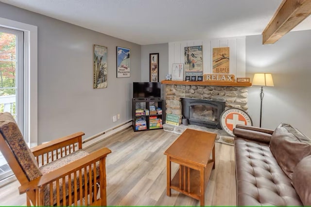 living room with baseboards, a stone fireplace, a baseboard radiator, light wood-style floors, and beamed ceiling