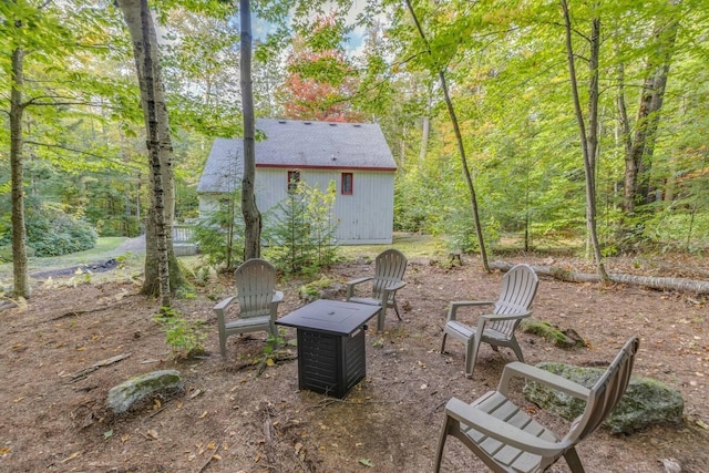 view of yard featuring a storage shed, an outdoor structure, and a fire pit